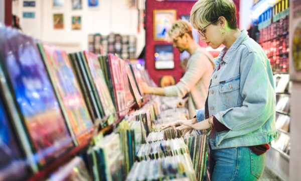 Young Woman Choosing Vintage Vinyl LP In Records Shop Young Woman And Man Browsing Through Vintage Discs and Choosing Vinyl LP In Records Shop. Couple Buying Music Albums.