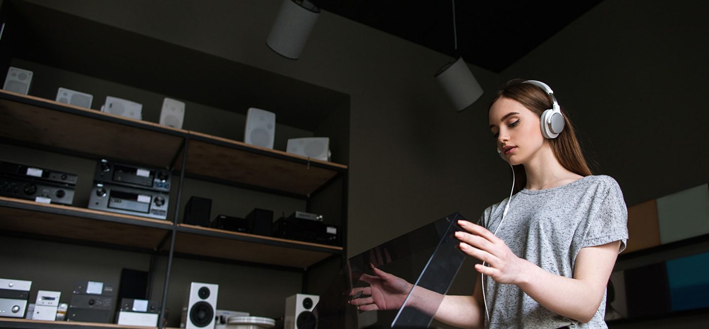 Young lady in music shop choosing vinyl records. Retro audio listening in headphones, modern hipster lifestyle
